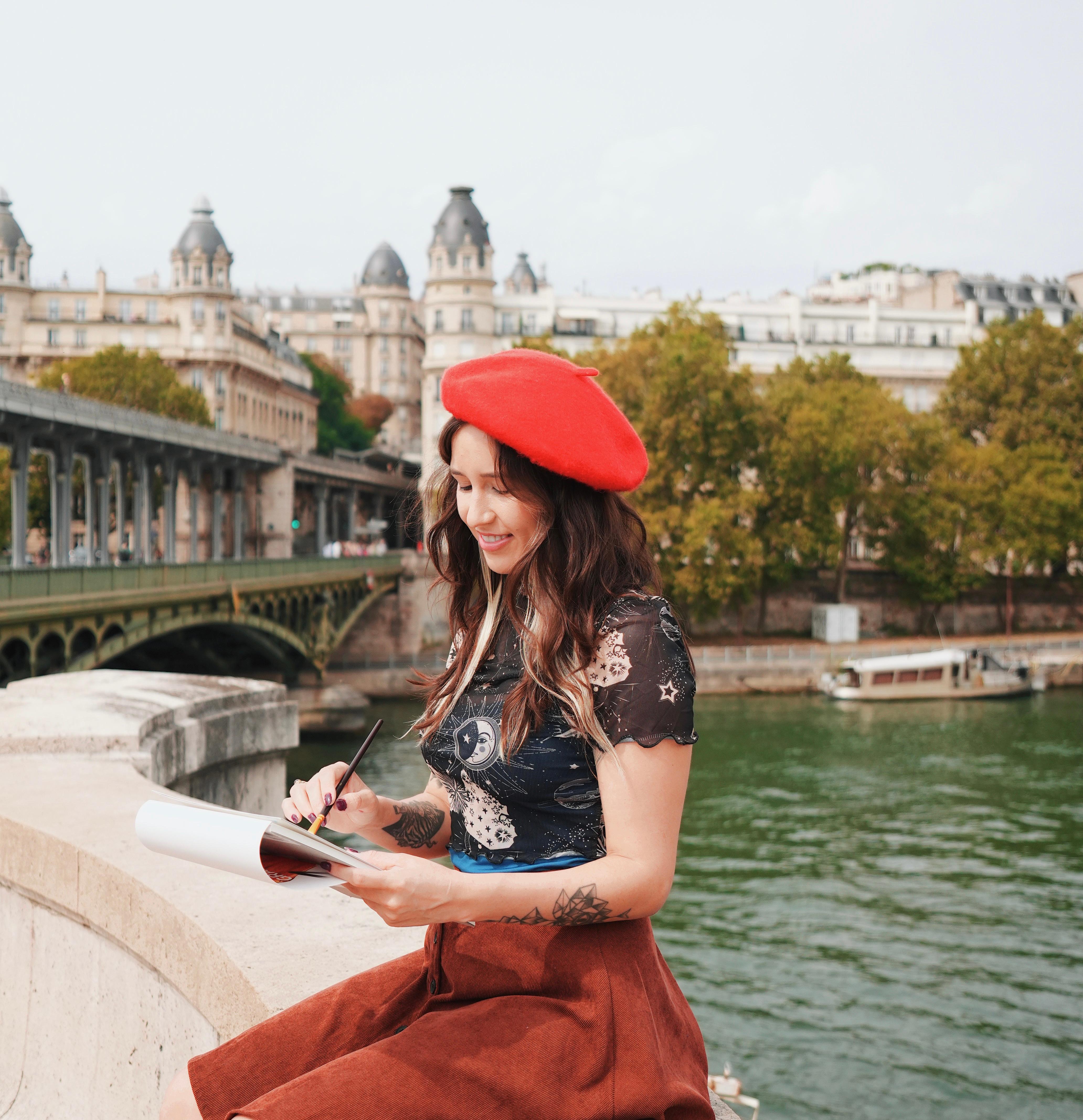 Paloma painting by the river, wearing a red beret